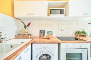 a kitchen with white cabinets and a washer and dryer at Créole Bay - Suites and Spa in Fort-de-France