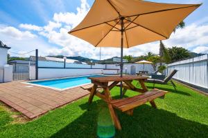 a picnic table with an umbrella next to a pool at Rolleston Motel Thames - Wenzel Motels in Thames