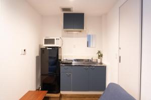 una pequeña cocina con nevera y microondas en Higashi Shinagawa Apartment, en Tokio