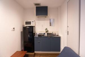 una pequeña cocina con nevera negra y microondas en Higashi Shinagawa Apartment, en Tokio