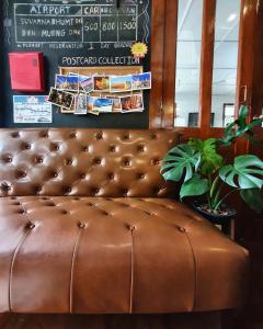 a brown leather couch sitting in a room with a plant at Dinsomon Hotel in Bangkok +42 photos
