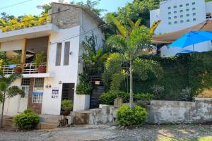 una casa blanca con una palmera delante de ella en Chacala Arrecifes 1 para 2 con Aire Acondicionado a solo 50 mts de la Playa ARF1, en Chacala