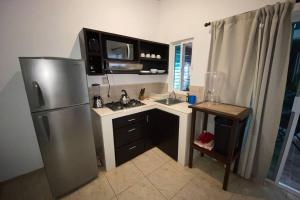 a small kitchen with a refrigerator and a sink at Chacala Arrecifes 2 para 4 a solo 50 mts de la Playa ARF2 in Chacala