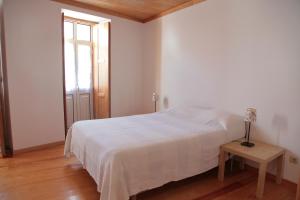 a white bedroom with a bed and a table at Casa das Tias in Manteigas