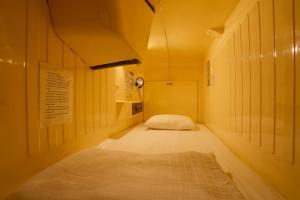 Un pequeño pasillo con una cama en una habitación en Capsule Land Yushima (Male Only), en Tokio