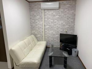 ein Wohnzimmer mit einem weißen Sofa und einem TV in der Unterkunft L House Miyako Island in Miyako-jima