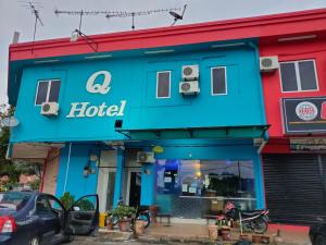 a blue hotel with a car parked in front of it at Q Hotel in Kuala Perlis