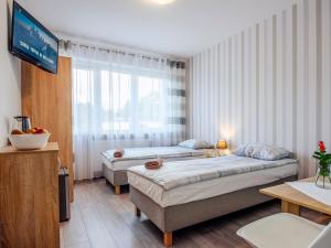 a hotel room with two beds and a television at Willa Lawenda in Ciechocinek