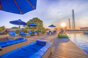a swimming pool with blue chairs and blue umbrellas at J4 Hotels Legian in Legian