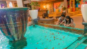 a man and a woman sitting in a pool of water at J4 Hotels Legian in Legian