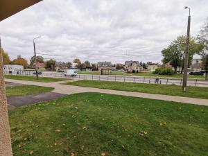 a grassy area with a sidewalk and a street at Cool Apartments in Liepāja