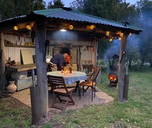 a man cooking in an outdoor kitchen with a table at Ionaforest Yurt in Wingello
