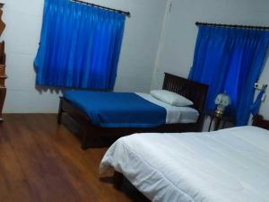 1 Schlafzimmer mit 2 Betten und blauen Vorhängen in der Unterkunft Mae Chaem Hotel and Resort in Mae Chaem