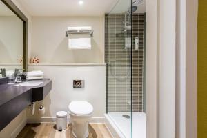 a bathroom with a toilet and a glass shower at Holiday Inn Brighton Seafront, an IHG Hotel in Brighton & Hove