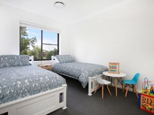 a bedroom with two beds and a table and a window at Rockwall I Pet Friendly I Fire Pit in Bundanoon