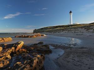 a beach with rocks and a lighthouse in the background at Marine Hotel in Buckie