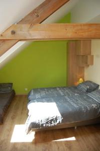 a bed in a room with a green wall at Le Clos des Haies, Silenrieux in Cerfontaine