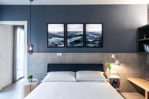 ein Schlafzimmer mit einem Bett mit vier Gemälden an der Wand in der Unterkunft SEI Garda Apartments in Peschiera del Garda