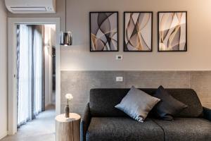 a living room with a couch and four paintings on the wall at SEI Garda Apartments in Peschiera del Garda