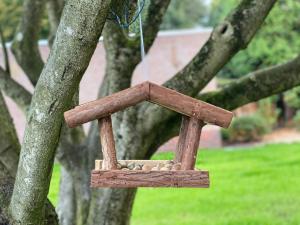 einem hölzernen Vogelfutter, der von einem Baum hängt in der Unterkunft Ferienwohnung Jette in Westerstede