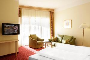 a hotel room with a bed and a couch and a tv at Hotel Alpen Residence in Ehrwald