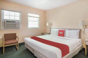 um quarto de hotel com uma cama grande e uma cadeira em OYO Hotel Durham West Hills em Durham