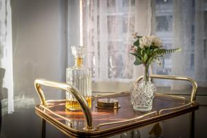 uma bandeja de ouro com um vaso de flores e uma garrafa de vidro em HiHome Hostel em Oviedo