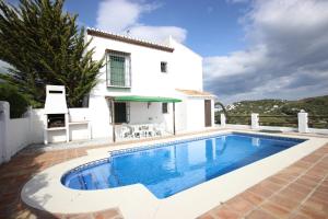 a villa with a swimming pool in front of a house at Casas de Cantoblanco in Viñuela