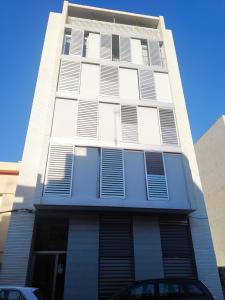 a tall white building with shuttered windows at Apartamentos Rosi in Benicarló
