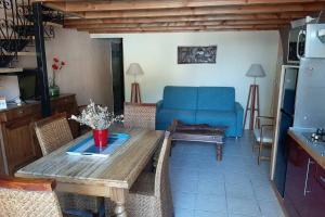 sala de estar con mesa de madera y sofá azul en Cave atelier dans ancien domaine viticole, en Moux