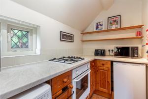 a kitchen with a stove top oven next to a window at Guest Homes - The Old Thatch in Bredon