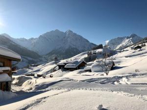 ein schneebedecktes Dorf mit Bergen im Hintergrund in der Unterkunft bi dr Gondamaika in Hirschegg