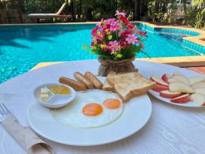 a plate of breakfast food on a table next to a pool at Ruen Ariya Resort in Mae Rim