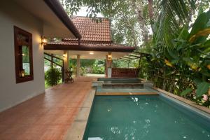a house with a swimming pool in the yard at Ruen Ariya Resort in Mae Rim