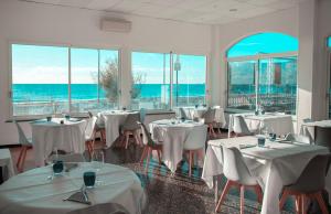 um restaurante com mesas e cadeiras brancas e o oceano em Hotel Ligure em Spotorno
