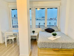 um quarto com uma cama, uma mesa e janelas em Pisos con Piscina Barrio Exclusivo-WizinkCenter em Madri