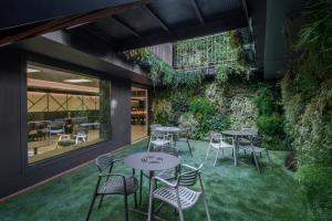 Hotel Olot Centre في أولوت: فناء به طاولات وكراسي وجدار أخضر