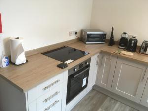 a kitchen with a counter with a stove and a microwave at Elmdon Lodge in Birmingham