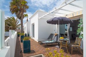 a patio with an umbrella and chairs and a table at B2 Bungalow Casitas de luz in Charco del Palo