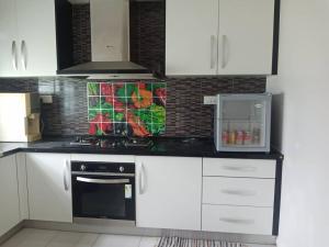 a kitchen with white cabinets and a stove top oven at 7eVenKitchen Hmestay in Jitra