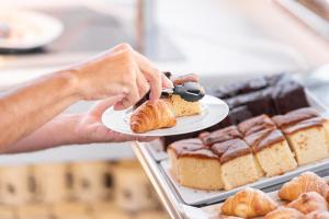 a person holding a plate with a piece of cake at Hotel La Milagrosa in Alicante