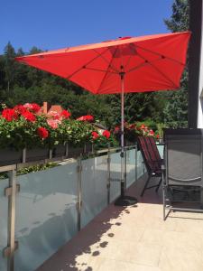 a red umbrella and a chair on a balcony with flowers at Ferienwohnung Abracadabra in Bad Pyrmont