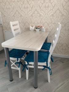 リヴィウにあるOK Apartments Yana Zhyzhkyの白いテーブルと椅子2脚(青い椅子付)