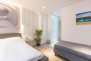 a white bedroom with a bed and a plant at Messe-Hotelzimmer-Einzimmerappartement in Leverkusen