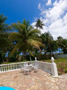 a table and chairs on a balcony with palm trees at AQUALUNA POUSADA in São Miguel dos Milagres