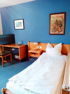 a bedroom with a bed and a desk and a blue wall at Excellent Hotel Hamburg in Hamburg