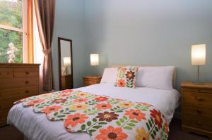 um quarto com uma cama com um cobertor florido em Keek Oot at 73 em Gourock