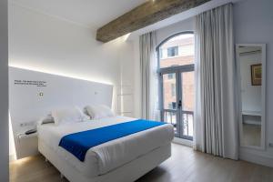 biała sypialnia z łóżkiem i dużym oknem w obiekcie Atarazanas Málaga Boutique Hotel w Maladze
