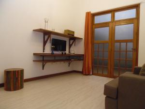 a living room with a door and a television at Flat aconchegante no Centro Histórico in São João del Rei
