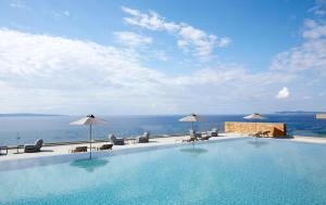a swimming pool with chairs and umbrellas and the ocean at Elix, Mar-Bella Collection in Perdika